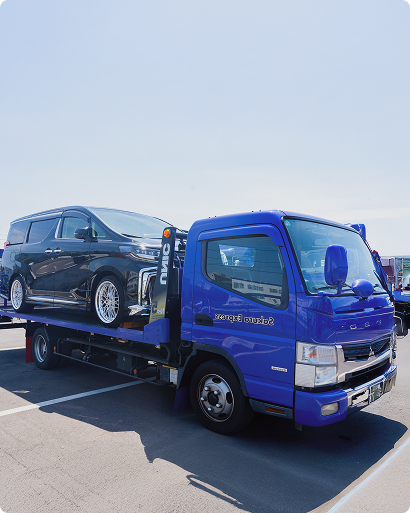 黒いミニバンを積載した青い車両運搬トラック